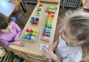 Na zdjęciu widzimy dziewczynki, które stoją przy ilustracji znaku zakazu palenia.