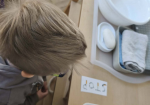 Na zdjęciu widzimy chłopca, który stoi przy ilustracji przedstawiającej zakaz palenia.