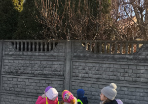 Na zdjęciu widzimy dzieci, które stoją przy drzewie z pąkami magnolii.