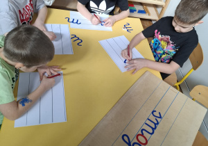 dzieci przy stoliku piszą napis smog