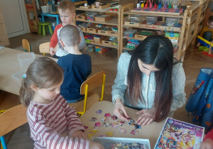 dziewczynka układa puzzle z wolontariuszką
