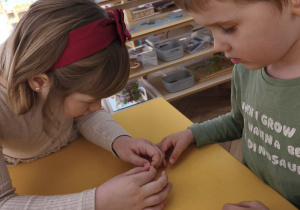 Chłopcy wykonujący bransoletki w parze z koleżanką