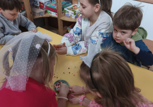 Chłopcy wykonujący bransoletki w parze z koleżanką