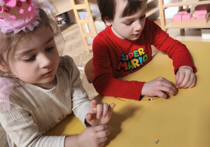 Chłopcy wykonujący bransoletki w parze z koleżanką