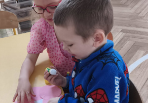 Chłopcy wykonujący bransoletki w parze z koleżanką