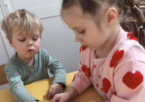 Chłopcy wykonujący bransoletki w parze z koleżanką