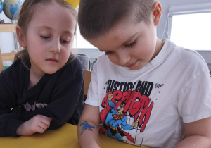 Chłopcy wykonujący bransoletki w parze z koleżanką