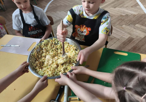 Dzieci mieszają i doprawiają sałatkę