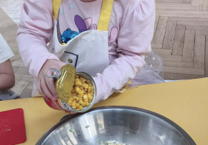 Dziecko dokłada kukurydze do sałatki