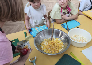 Dziecko dokłada kukurydze do sałatki