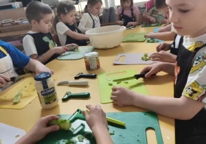 Dzieci obierają i kroją ogórki