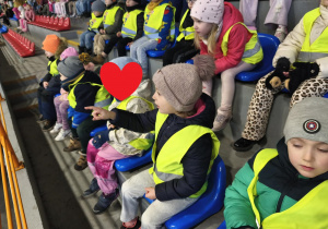 Na zdjęciu widzimy dzieci, które oglądają występy na lodzie.