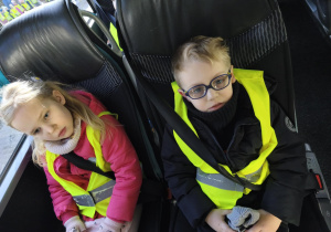 Na zdjęciu widzimy dwójkę dzieci siedzących w autokarze.