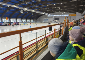 Na zdjęciu widzimy dzieci, które oglądają występy na lodzie.