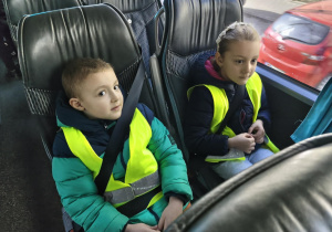 Na zdjęciu widzimy dwójkę dzieci siedzących w autokarze.