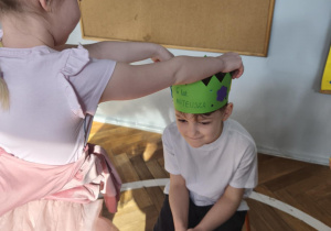 Na zdjęciu widzimy dziewczynkę, która kładzie na głowie Jubilata koronę.