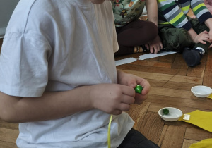 Na zdjęciu widzimy chłopca, który nawleka na tasiemkę swoją "linię życia".