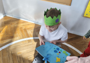 Na zdjęciu widzimy dziewczynkę, która wręcza Jubilatowi książkę z laurkami.