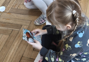 Na zdjęciu widzimy dziewczynkę, która ogląda zdjęcie Jubilata.