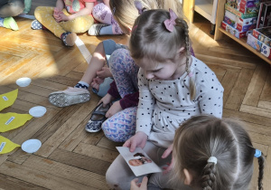 Na zdjęciu widzimy dziewczynkę, która ogląda zdjęcie Jubilata.