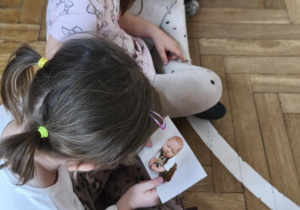 Na zdjęciu widzimy dziewczynkę, która ogląda zdjęcie Jubilata.