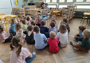 dzieci patrzą na kobietę i książki