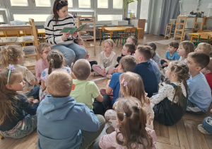 kobieta czyta książkę grupie dzieci