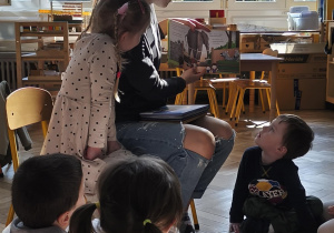 Na zdjęciu widzimy mamę Anastazji, która czyta dzieciom książkę o Jadzi.