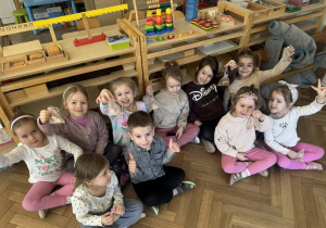 Zdjęcie przedstawia chłopca siedzącego wśród dziewczynek.