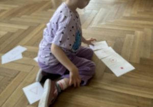 Zdjęcie przedstawia dziewczynkę dokładającą kartkę z kodem do innych kartek.