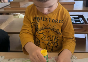 Zdjęcie przedstawia chłopca podczas wykonywania pracy plastycznej.