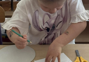 Zdjęcie przedstawia dziewczynkę podczas odrysowywania trójkąta.