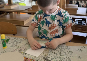 Zdjęcie przedstawia chłopca podczas wykonywania pracy plastycznej.