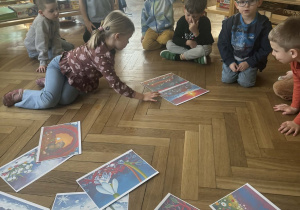 Zdjęcie przedstawia dziewczynkę dokładającą kartkę z obrazkiem do innych kartek.