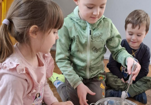 Na zdjęciu widzimy chłopca, który miesza ilustrację pogody marcowej w garnku za pomocą łyżki.