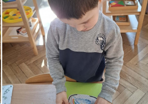 Na zdjęciu widzimy chłopca, który wykonuje prace plastyczną.