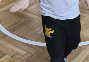 Na zdjęciu widzimy chłopca, który wykonuje ćwiczenia sprawnościowe.