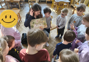 Na zdjęciu widzimy dzieci, które oglądają ilustrację w książce.