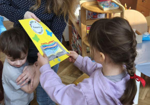 Na zdjęciu widzimy dziewczynkę, która przekazuje mamie Tymona podziękowanie za zaangażowanie w akcję "Głośne Czytanie" w grupie.