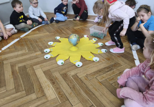 Na zdjęciu widzimy dziewczynkę, które wkłada koraliki do miseczek - symbolizujących minione lata.