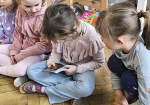 Na zdjęciu widzimy dzieci oglądające zdjęcia Jubilatki z różnych etapów życia.