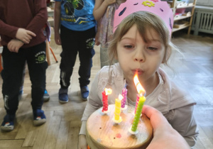 Na zdjęciu widzimy Jubilatkę dmuchającą świeczki.