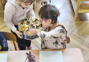 Na zdjęciu widzimy Jubilatkę częstującą dziewczynkę babeczką.