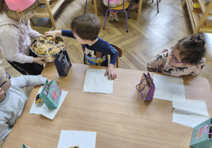Na zdjęciu widzimy Jubilatkę częstującą chłopca babeczką.
