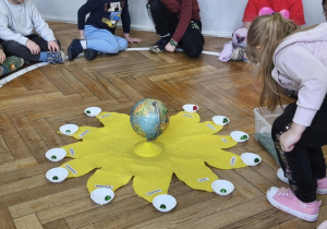 Na zdjęciu widzimy dziewczynkę, które wkłada koraliki do miseczek - symbolizujących minione lata.