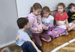 Na zdjęciu widzimy dzieci oglądające zdjęcia Jubilatki z różnych etapów życia.