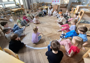 troje dzieci układa wieże z klocków, pozostałe dzieci tupią nogami