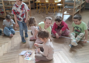 dziewczynka układa wzór z kolorowych koralików, pozostałe dzieci przeszkadzają jej