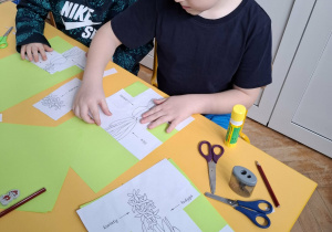 chłopcy układją budowę kwiata na kartkę