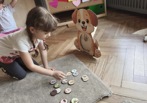 Dziecko sprawdza co pies może jeść wkładając wybrany produkt do psiej zabawki